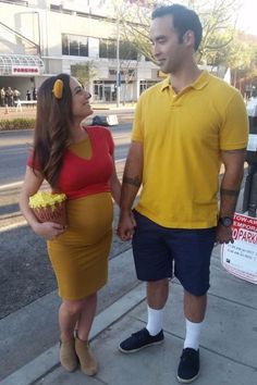 a man and woman dressed in costumes standing next to each other on the sidewalk near a parking meter