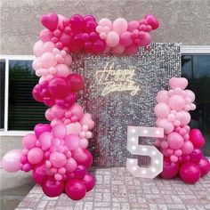 the balloon arch is decorated with pink and white balloons, which spell it's 55th birthday