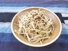 a bowl filled with sprouts on top of a blue and white table cloth