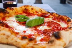 a close up of a pizza on a plate with sauce and green leafy garnish