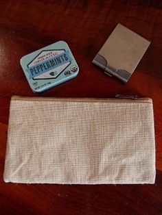 an empty zippered pouch sitting on top of a wooden table next to a lighter