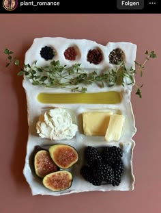 figurines and cheese are arranged on a platter with herbs, berries, and other ingredients