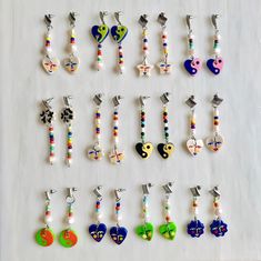 a collection of earrings with different designs and colors are displayed on a white table top