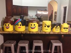 a kitchen counter topped with yellow legos and stools next to a refrigerator freezer