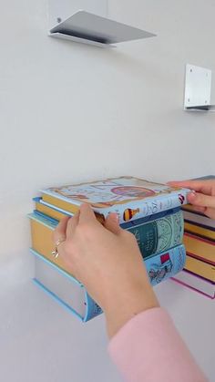 a person is placing books on the wall to hold them in order to reach for it