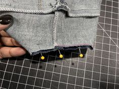 someone is stitching holes in the back of their jean shorts with yellow beads on them