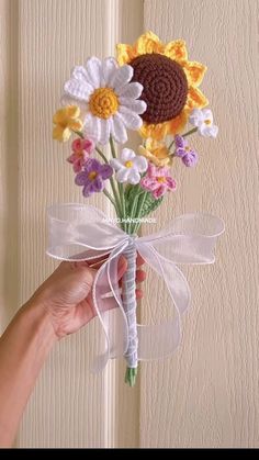 a person holding a bouquet of flowers in front of a white door with a ribbon