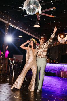 a man and woman dancing on the dance floor at a wedding in front of a disco ball