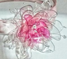 a pink flower is sitting on top of a headband with ribbon and crystal beads