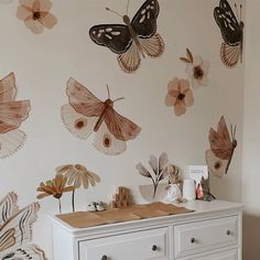 a white dresser sitting next to a wall with butterflies on it