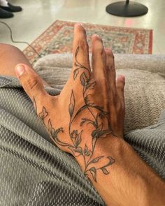 a man's hand with tattoos on it sitting on top of a couch next to a rug