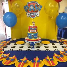 a paw patrol themed birthday party with blue and yellow plates, balloons, and cake