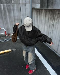 a little boy in a black jacket and red shoes is walking towards a parking lot