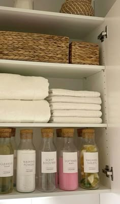 towels and bath products are on shelves in a bathroom closet, with wicker baskets above them