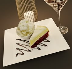 there is a piece of cake and ice cream on the plate next to two wine glasses