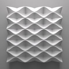 an abstract white wall sculpture with wavy lines on it's face and bottom, against a gray background