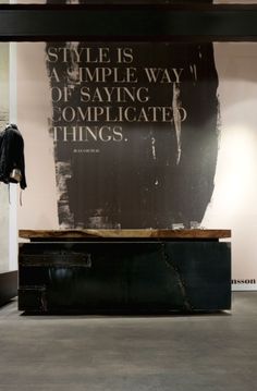 a black piece of luggage sitting on top of a wooden table in front of a poster