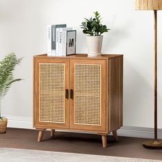 a wooden cabinet sitting next to a lamp and potted plant in a living room