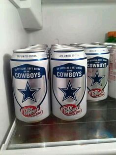 four cans of beer sitting on top of an open refrigerator