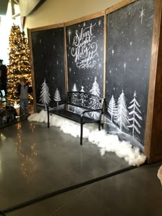 a couple of benches sitting in front of a chalk board christmas tree with snow on it