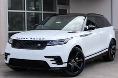 a white range rover is parked in front of a building with large windows and black rims