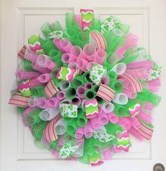 a pink and green wreath on the front door