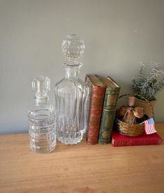 three glass bottles sitting on top of a wooden table next to books and an american flag