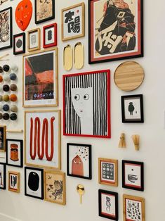 a wall with many framed pictures on it and various other items hanging on the wall