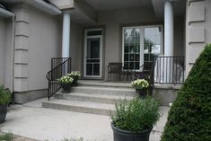 two planters with flowers are on the front steps of a house that has stairs leading up to it