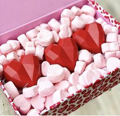 there are many hearts in the box with marshmallows on it and one is pink