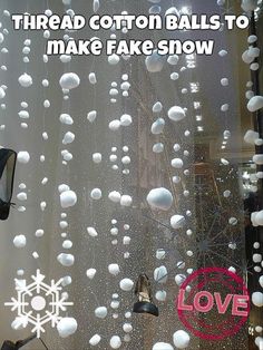 the window is covered with white balls and snowflakes that are hanging from it's side