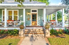 a small blue house with white trim on the front porch and steps leading up to it