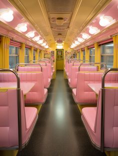 the inside of a train with pink seats and yellow curtains on both sides, along with black flooring