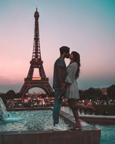 a man and woman kissing in front of the eiffel tower at dusk, paris