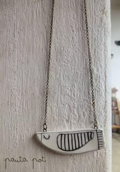 a white and black necklace hanging from a chain on a wall with an animal design