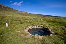 there is a hole in the ground with grass and rocks around it that looks like an underground well