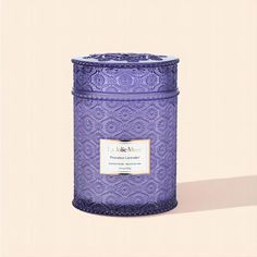 a large purple candle with a label on it's lid sitting in front of a beige background