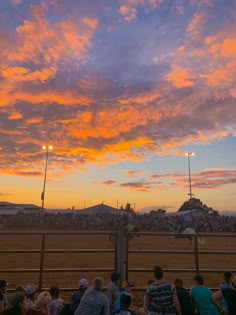 people are watching the sunset at a horse race