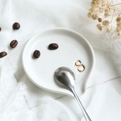 a white plate topped with coffee beans next to a spoon