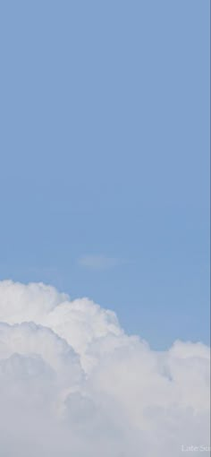 an airplane flying high in the sky with clouds behind it and another plane on the ground below