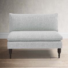 a white couch sitting on top of a hard wood floor next to a gray wall