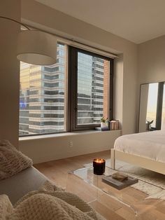 a bedroom with a large window and a bed next to it in front of a cityscape