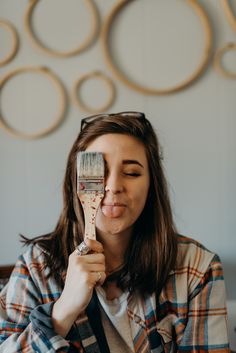 a woman holding a paintbrush in front of her face