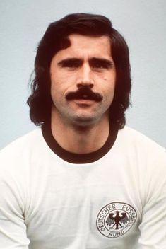 a man with long hair and a moustache wearing a white t - shirt