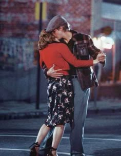 a man and woman kissing on the street at night with words written in arabic above them