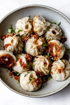 a white bowl filled with dumplings covered in sauce