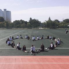 a group of people sitting in the middle of a basketball court on top of a field