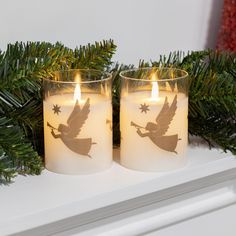 two lit candles sitting on top of a mantle