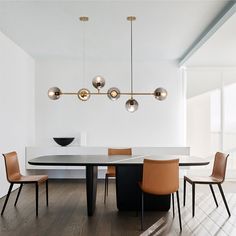 a dining room table with four chairs and a chandelier hanging from the ceiling