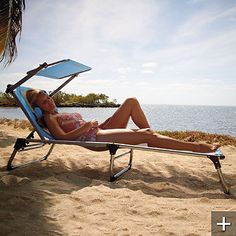 a woman laying in a chair on the beach